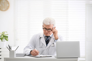 Poster - Senior doctor working at table in office