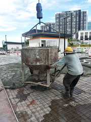 Group of construction workers pouring wet concrete using the mobile crane bucket the construction site.  