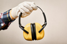 Worker's Hand Giving Protective Earphones: Hearing Protection And Labor Protection Concept