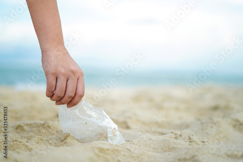 Woman hand is picking up plastic bag, waste and garbage from the beach to reduce and safe the planet to protect environment problem as volunteer and human responsibility