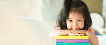 Panoramic Portrait Of Asian Girl Toddler Smiling Put Her Chin Over Her Hands On The Books Stack. Education Encourage Concept.