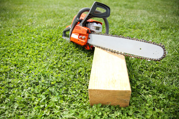 Wall Mural -  orange chainsaw on grass close up with copy space.