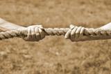 Fototapeta  - Two men's hands pull the rope each in his own direction. The concept of dispute, conflict and force. Toning