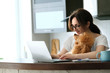 The young woman is working remotely. Young woman with her dog working using a laptop at home. Concept of the workplace at home, working remotely.
