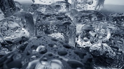 Wall Mural - Melted ice cubes close up. Camera moves through ice cubes with water drops over dark background. UHD, 4K