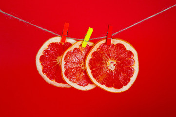 Chips of dried grapefruit sliced in thin circles, shot on a red background. Background for vegetarianism, healthy and wholesome food.