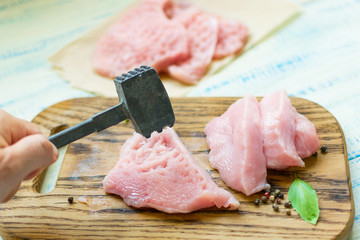 Preparation of chops. Hand with a hammer beats a meat turkey, chicken fillet.