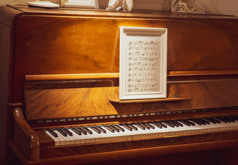 wooden piano with sheet music in a picture frame 