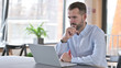 © stockbakers - Pensive Young Man Thinking while Working on Laptop