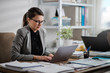 © Suteren Studio - Attractive young businesswoman working on a computer at the office.  Confident entrepreneur on the job.