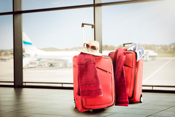 Summer red suitcase on airport and sunny warm day 