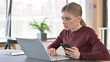 © stockbakers - Young Woman using Laptop and Smartphone in Office