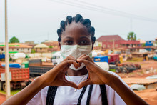 Young Black Beautiful Lady Wearing A Nose Mask And Giving A Love Sign With Her Hand