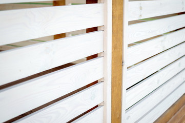 A plank classic wooden fence is painted white. Exterior of a summer cafe