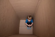 © spritnyuk - bullied hunched child sitting in a box, seeking for help and refuge from domestic violence in his cardboard home, contrast effects