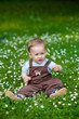 © Elena  - Charming boy among green grass and beautiful daisies on a summer day. A small child has fun in the fresh air. Baby explores the nature of