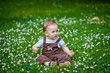 © Elena  - Charming boy among green grass and beautiful daisies on a summer day. A small child has fun in the fresh air. Baby explores the nature of