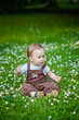 © Elena  - Charming boy among green grass and beautiful daisies on a summer day. A small child has fun in the fresh air. Baby explores the nature of