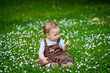© Elena  - Charming boy among green grass and beautiful daisies on a summer day. A small child has fun in the fresh air. Baby explores the nature of