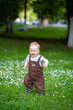 © Elena  - A charming boy among green grass and beautiful daisies on a summer day. The kid explores nature. The first steps of the baby on the grass. First independent steps.