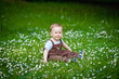© Elena  - Charming boy among green grass and beautiful daisies on a summer day. A small child has fun in the fresh air. Baby explores the nature of