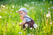 © Elena  - Beautiful little boy with long hair in the park blowing dandelion at sunset. Child playing with dandelion in spring park