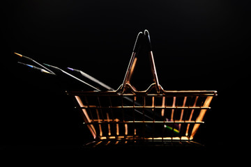 golden metal mini-basket with pencils for a grocery store on a dark background with reflection