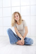 © amedeoemaja - portrait of young woman sitting on the floor dressed casual with curly and long red hair isolated on white window background