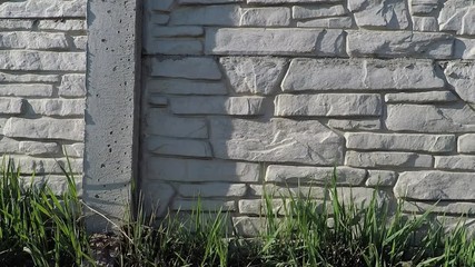 Wall Mural - background texture grey fence made of cement with the imtyping of natural stone and green grass in the foreground