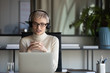 © fizkes - Focused pleasant 30s businesswoman in eyeglasses wearing wireless headphones with microphone, looking at laptop screen, holding video call negotiations meeting online with partners alone in office.