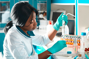 Wall Mural - African scientist or graduate student in lab coat and protective wear performs PCR testing of patient samples in modern test laboratory. Developing pcr kits to diagnose Covid-19 patients.