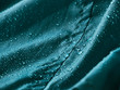 Rain water droplets on turquoise fiber waterproof fabric. Turquoise background.