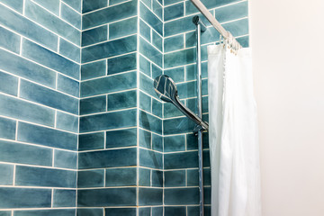 Modern minimalistic bathroom with blue green tiles tiled shower and head in bright room with curtain