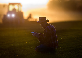 Poster - Farmer with tablet squatting in front of tractor