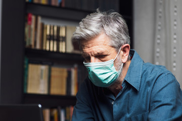 Senior man wearing face mask at home