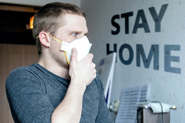 young man in ffp1 respirator against the background of the wall with the inscription 