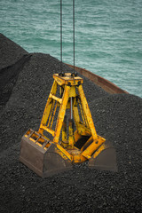 Wall Mural - Loading coal from cargo barges onto a bulk vessel using ship cranes  in offshore coal cargo terminal.
