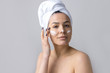 © Mountains Hunter - Beauty portrait of woman in white towel on head applies cream to the face. Skincare cleansing eco organic cosmetic spa relax concept.