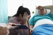 © H_Ko - Upset woman sitting near man in hospital bed. Resuscitation measures for critically ill patients. Assistance to victims car accidents. Rehabilitation procedures. Resuscitation and intensive care unit
