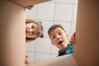 © Pixel-Shot - Curious children looking inside cardboard box, bottom view