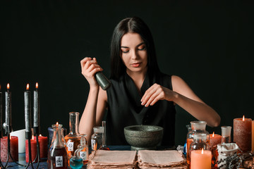 Wall Mural - Female alchemist making potion on dark background