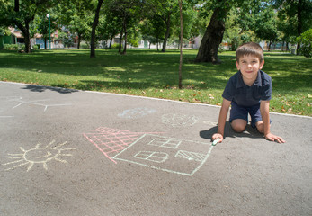 Child drawing sun and house on asphalt