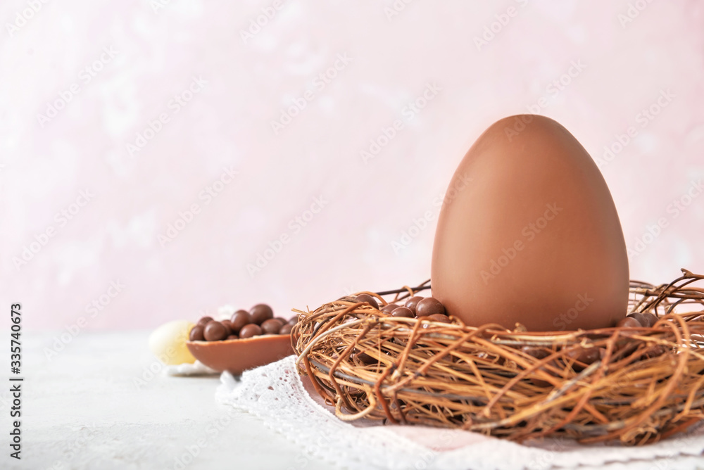 Nest with tasty chocolate Easter egg on table