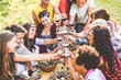 © DisobeyArt - Group of friends enjoying picnic while drinking red wine and eating snacks appetizer outdoor - Young people cheering and having fun together - Focus on left bottom guy face