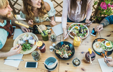 Young people eating brunch and drinking smoothie bowl at eco plastic-free cafeteria - Happy people having a healthy lunch and chatting together - Food trends concept - Focus on table dishes