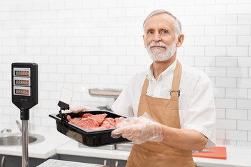 Wall Mural - Male butcher demonstrating meat in supermarket.