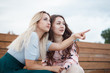 © Kseniia - Two women sitting on stairs outdoor and pointing finger