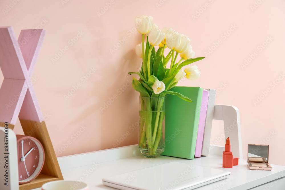 Modern stylish workplace with flowers near color wall