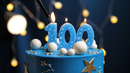 Birthday cake number 100 stars sky and moon concept, blue candle is fire by lighter. Copy space on right side of screen. Close-up