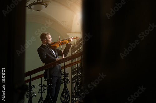elegant talented professional violinist performing classical music, handsome guy in formal suit holding violin. classical music and instruments concept